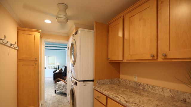 washroom featuring light hardwood / wood-style floors, cabinets, stacked washing maching and dryer, and ornamental molding