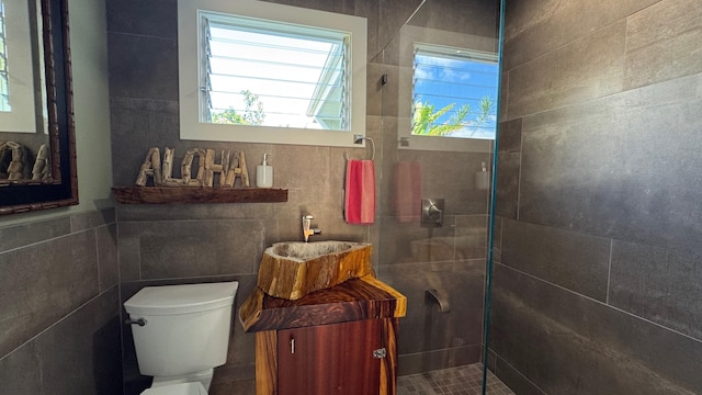 bathroom featuring toilet, tile walls, and tiled shower