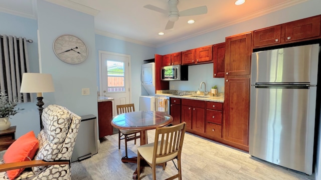 kitchen with light hardwood / wood-style flooring, stainless steel appliances, stacked washer / drying machine, and ornamental molding