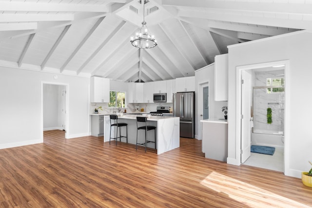 kitchen featuring a breakfast bar, a kitchen island, pendant lighting, stainless steel appliances, and white cabinets