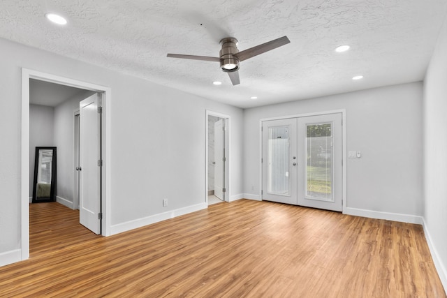 spare room with french doors, ceiling fan, light hardwood / wood-style flooring, and a textured ceiling