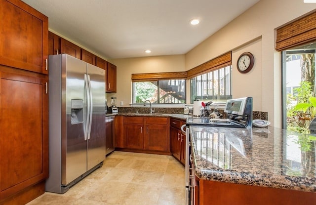 kitchen featuring sink, stainless steel appliances, and dark stone counters