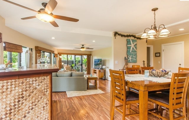 dining room featuring a wealth of natural light, ceiling fan with notable chandelier, and hardwood / wood-style flooring