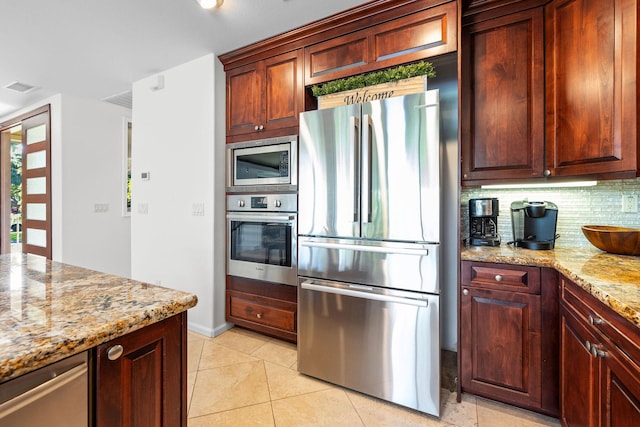 kitchen featuring tasteful backsplash, appliances with stainless steel finishes, light tile patterned floors, and light stone counters