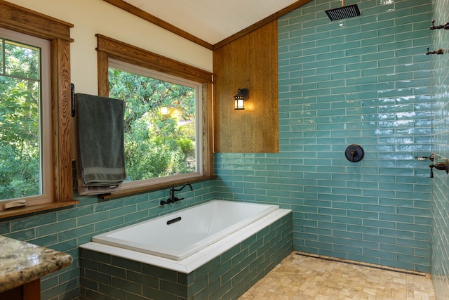 bathroom with tile walls, crown molding, and tiled tub