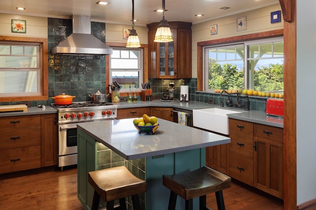 kitchen featuring a center island, wall chimney exhaust hood, dark hardwood / wood-style flooring, a kitchen bar, and appliances with stainless steel finishes