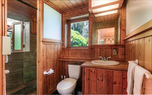 bathroom with toilet, wood walls, a skylight, wood ceiling, and vanity