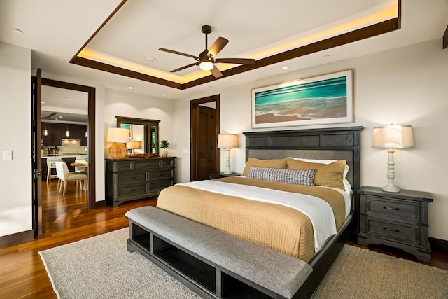 bedroom featuring ceiling fan, dark hardwood / wood-style floors, and a raised ceiling