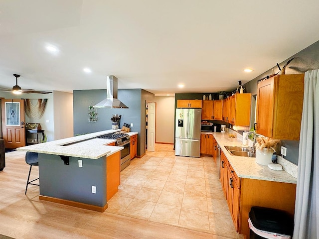 kitchen featuring sink, a breakfast bar area, ceiling fan, island range hood, and stainless steel appliances