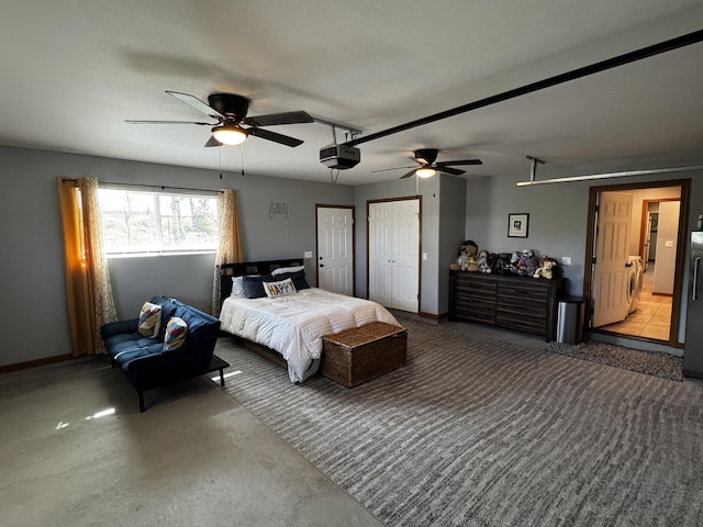 bedroom with washer / clothes dryer, ceiling fan, concrete floors, and two closets