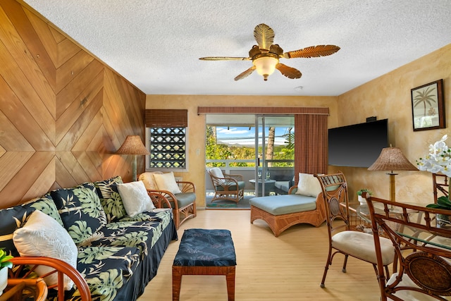 living room featuring a textured ceiling, ceiling fan, and wood walls