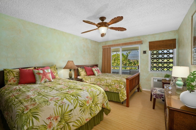 bedroom featuring access to exterior, a textured ceiling, light hardwood / wood-style floors, and ceiling fan