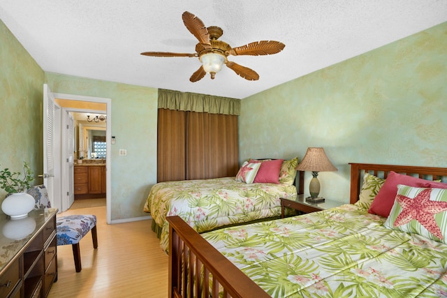 bedroom with ceiling fan, connected bathroom, and light hardwood / wood-style flooring