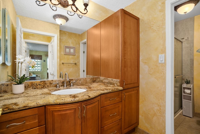 bathroom featuring vanity, a shower with door, and a textured ceiling