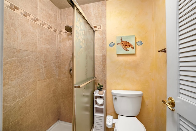 bathroom featuring a shower with shower door and toilet