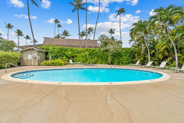 view of pool featuring a shed and a patio