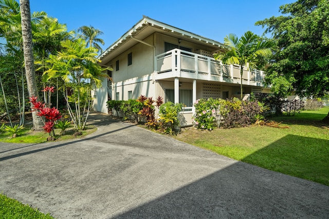 view of side of home with a lawn and a balcony