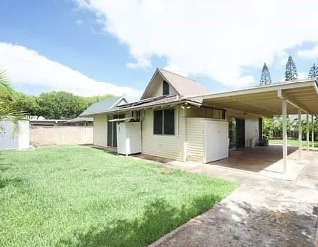 back of house featuring a carport and a lawn