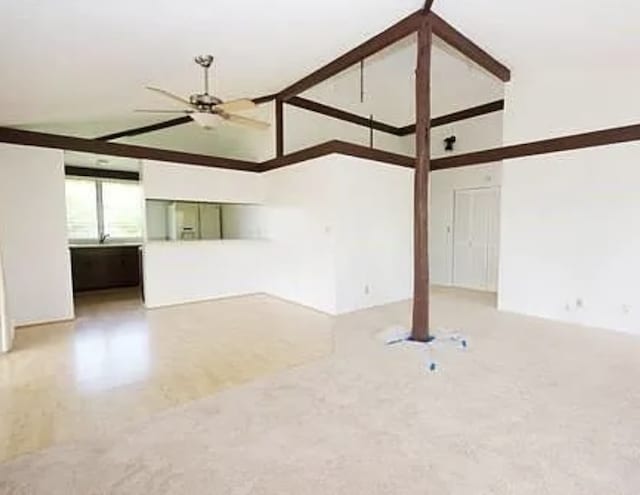 unfurnished living room featuring ceiling fan and a high ceiling