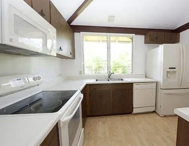 kitchen with dark brown cabinets, sink, white appliances, and light wood-type flooring