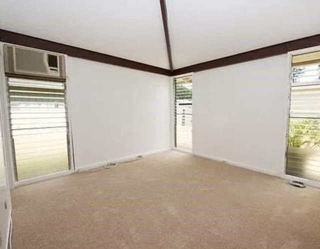 unfurnished room featuring vaulted ceiling with beams, a healthy amount of sunlight, and light carpet