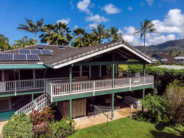 back of property with solar panels, a yard, a patio, and a wooden deck