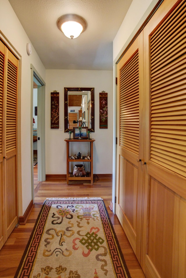 hall featuring a textured ceiling and light hardwood / wood-style flooring