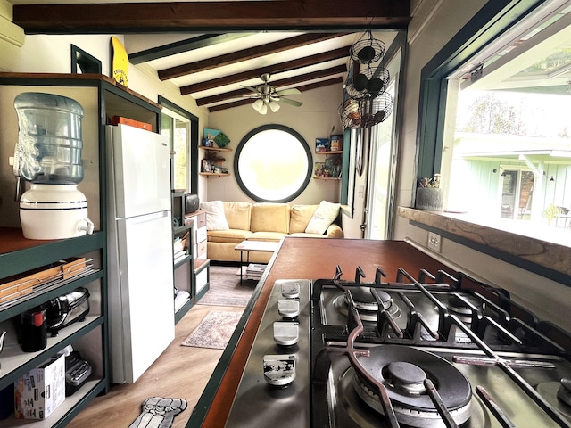 kitchen with light wood finished floors, ceiling fan, freestanding refrigerator, stainless steel gas cooktop, and beam ceiling