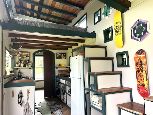 kitchen featuring arched walkways, stainless steel gas cooktop, wood finished floors, wood ceiling, and freestanding refrigerator