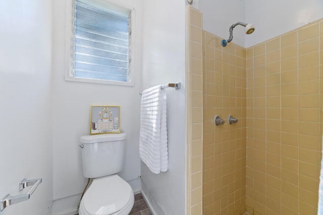 bathroom featuring tiled shower and toilet