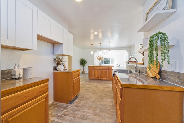 kitchen with white cabinets, pendant lighting, kitchen peninsula, and sink