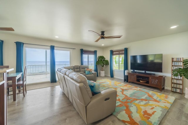 living room with ceiling fan, light hardwood / wood-style floors, and a water view