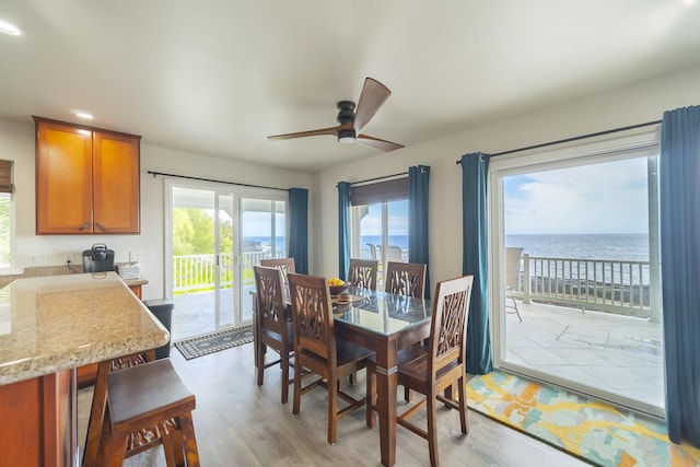 dining space featuring ceiling fan, a water view, and light hardwood / wood-style flooring