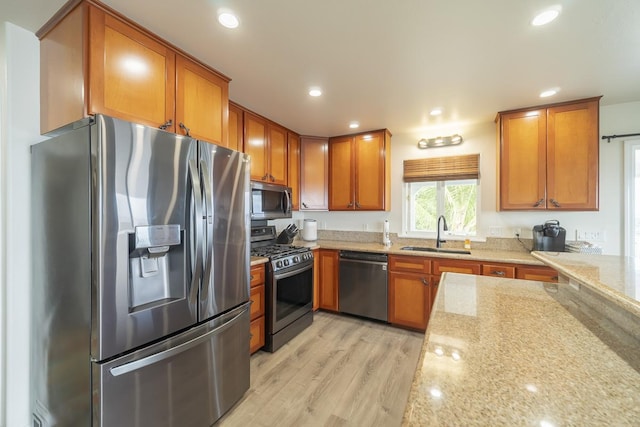 kitchen featuring light hardwood / wood-style flooring, stainless steel appliances, light stone counters, and sink