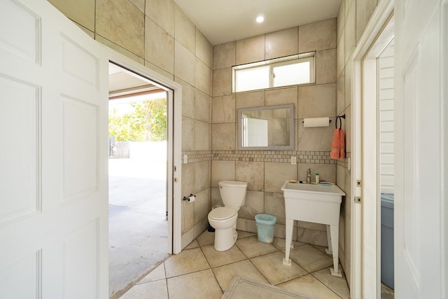 bathroom featuring tile patterned flooring, toilet, and tile walls