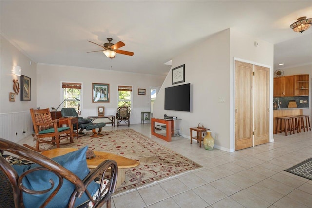 tiled living room with ceiling fan and crown molding