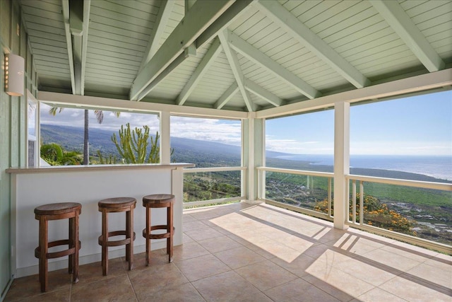 sunroom / solarium featuring beamed ceiling, a healthy amount of sunlight, and a water and mountain view