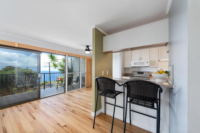 kitchen with stainless steel range with electric stovetop, a water view, crown molding, light hardwood / wood-style floors, and white cabinetry