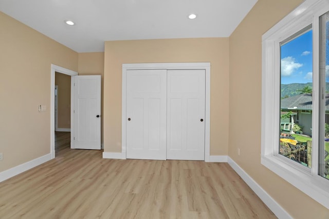 unfurnished bedroom featuring recessed lighting, a closet, light wood-type flooring, and baseboards