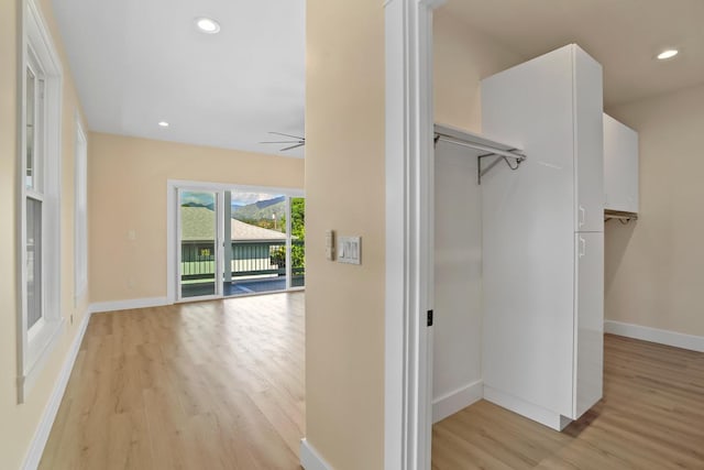 corridor featuring light wood-style flooring, baseboards, and recessed lighting