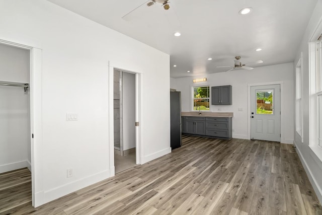 interior space featuring light wood finished floors, recessed lighting, a sink, ceiling fan, and baseboards