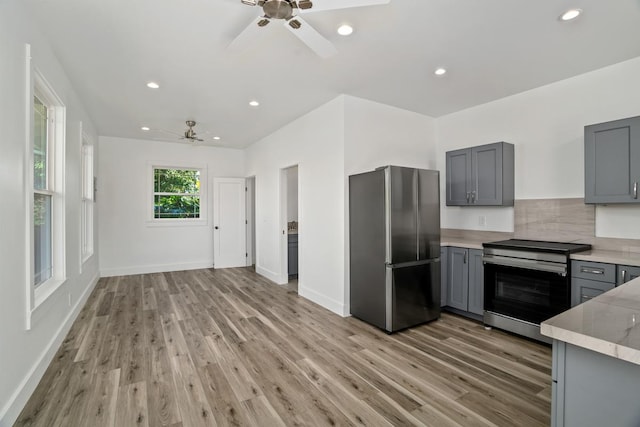 kitchen featuring light wood finished floors, appliances with stainless steel finishes, backsplash, and gray cabinetry