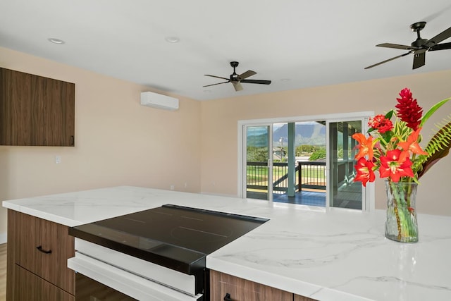 kitchen with ceiling fan, range with electric cooktop, a wall mounted AC, light stone countertops, and modern cabinets