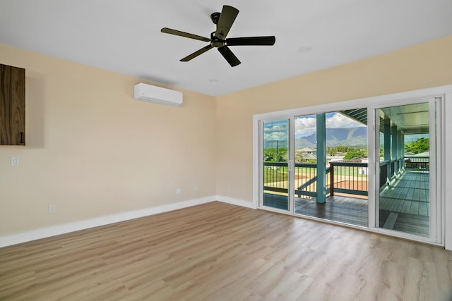 spare room with a ceiling fan, light wood-style flooring, baseboards, and a wall mounted AC