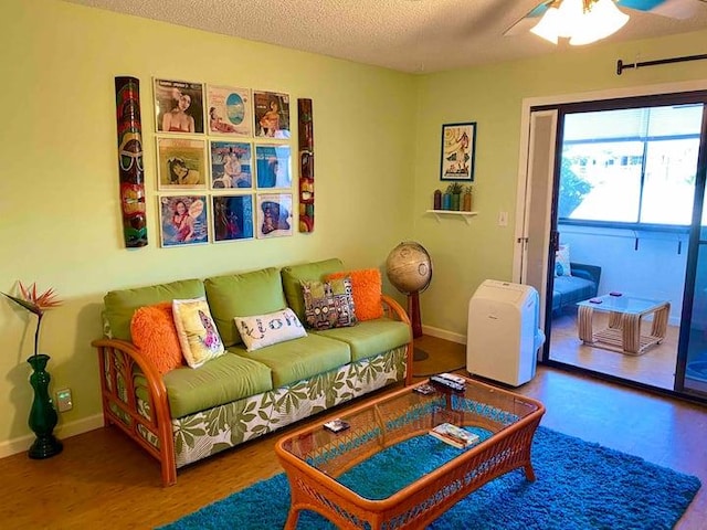 living room featuring ceiling fan, hardwood / wood-style floors, and a textured ceiling