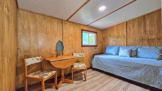 bedroom with light wood-type flooring and wood walls