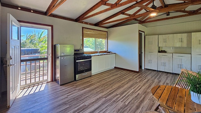 kitchen with vaulted ceiling with beams, light hardwood / wood-style floors, stainless steel appliances, and a wealth of natural light