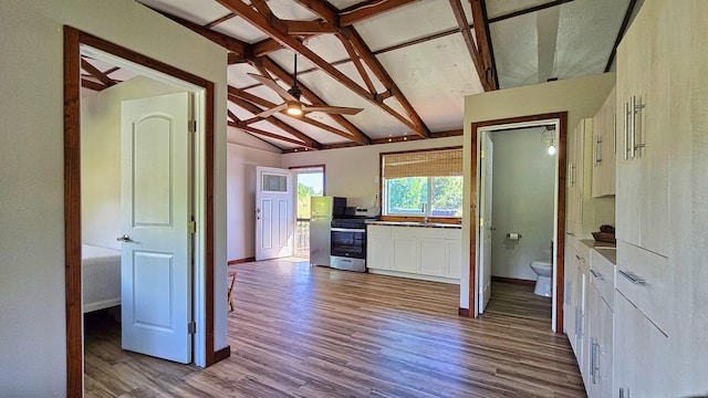 kitchen featuring stainless steel range, sink, beamed ceiling, white cabinets, and hardwood / wood-style flooring