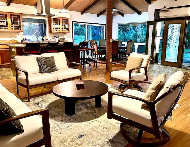 living room with a wall mounted air conditioner, beamed ceiling, indoor bar, and light wood-type flooring