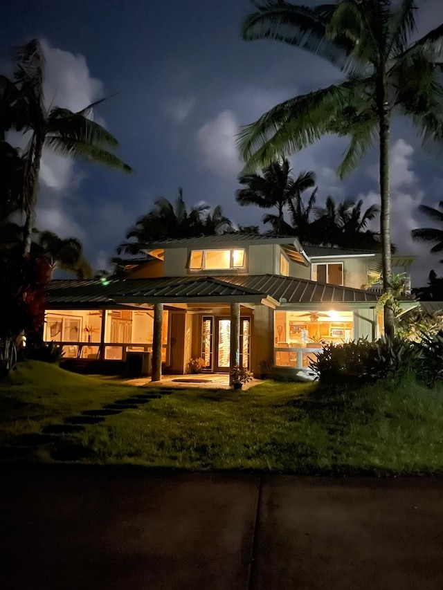 back house at twilight featuring a lawn